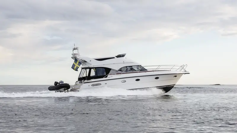 Motor yacht under way with a black RIB on the swim platform, archipelago behind