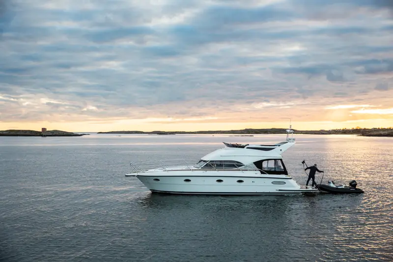 Motor yacht on calm evening water with the tender at the swim platform, backlit